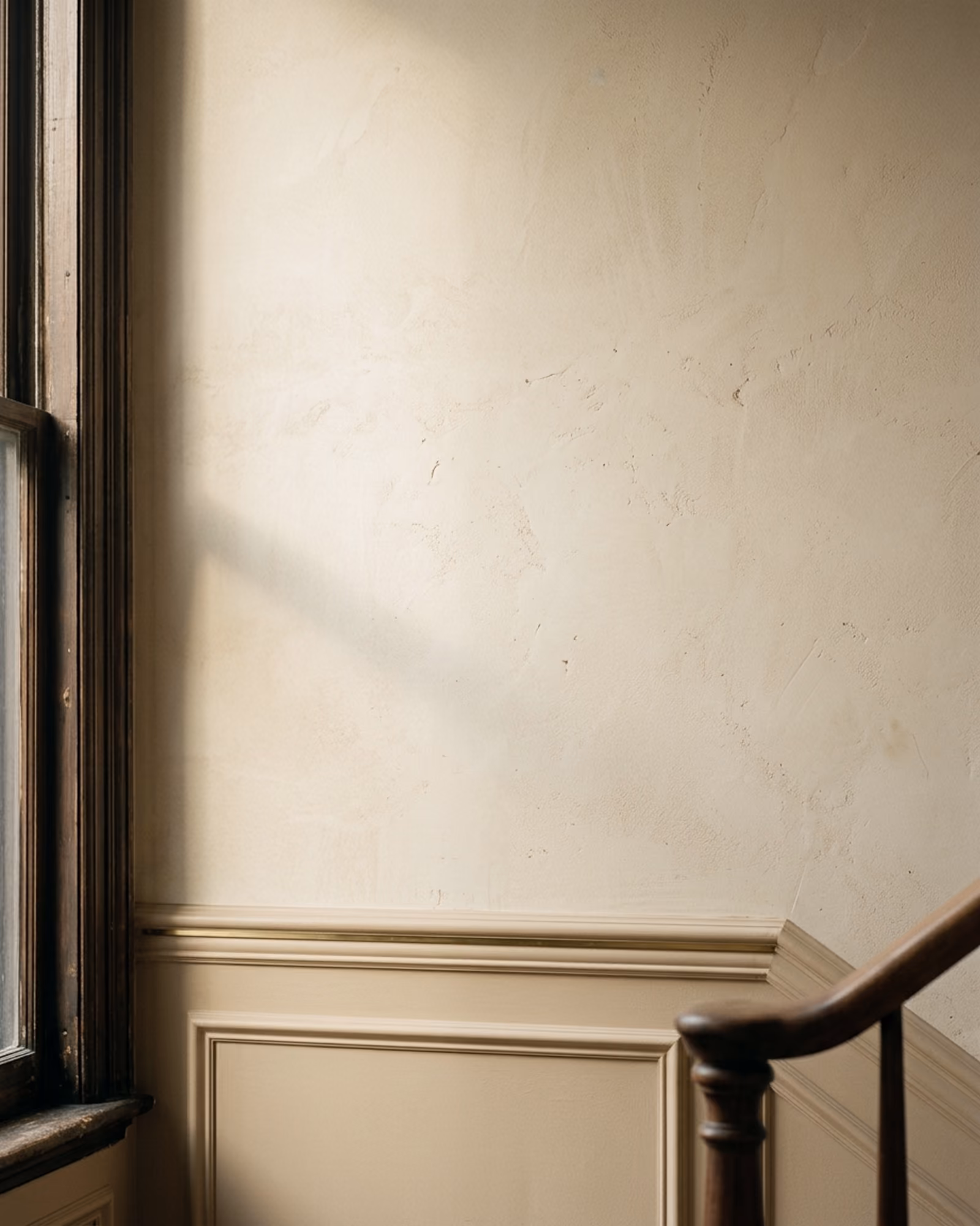 Mur de plâtre crème, moulure et rampe d’escalier en bois
